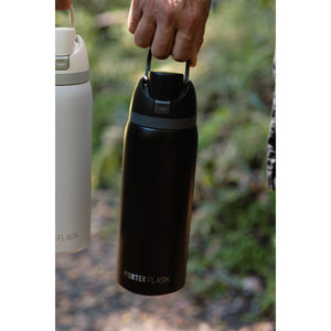 Botella Térmica Porter Flask Acero Inoxidable 700 ml — botella negra sostenida por el asa al aire libre
